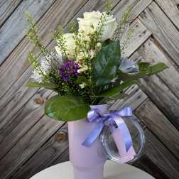 White and purple bouquet in a lavender tumbler with a ribbon