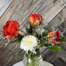 Red tulips and a white chrysanthemum in a glass vase