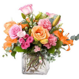 Mixed bouquet of pink and orange flowers in a clear glass vase