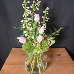Pink tulips and green berry stems in a glass vase