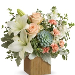 Arrangement of white lilies, peach roses, carnations, and a succulent in a wooden cube vase
