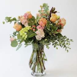 Mixed bouquet of peach and pink roses in a clear glass vase