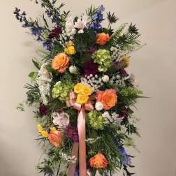 Tall standing floral spray with multicolored blooms and a pink ribbon