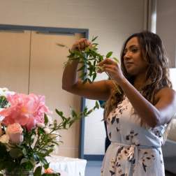 Woman arranging pink flowers and greenery at a table