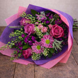 Bouquet of pink roses and purple flowers wrapped in pink and purple paper