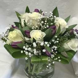 Bouquet of white roses and purple tulips in a glass vase