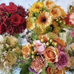 Assorted bouquets of roses, gerbera daisies, and carnations in warm colors