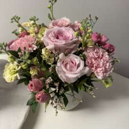 Pink roses and carnations arranged in a white vase