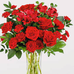 Red roses and carnations in a clear glass vase