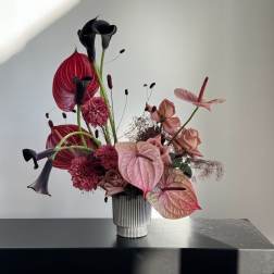 Pink and black floral arrangement in a ribbed vase