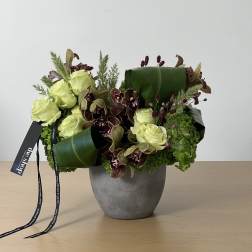 Green and burgundy floral arrangement in a gray vase