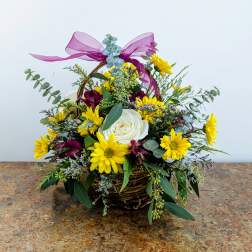Basket arrangement with yellow daisies and a white rose, topped with a purple ribbon