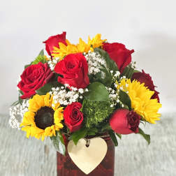 Bouquet of red roses and yellow sunflowers in a square vase with a heart tag