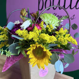 Sunflower bouquet with yellow and purple flowers in a gift bag