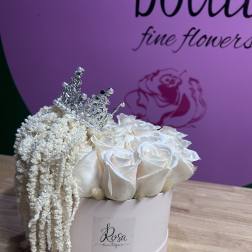 White roses in a round box with a silver tiara and draping white filler