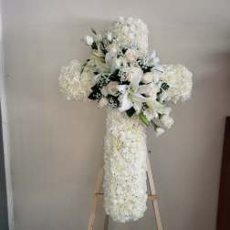 White floral cross arrangement on a wooden easel