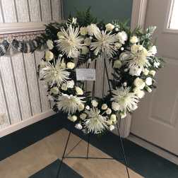 White floral wreath on a black easel stand