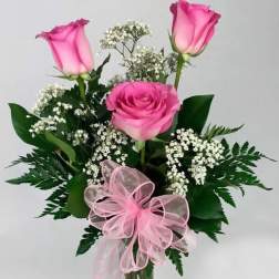 Pink roses in a clear glass vase with baby's breath and a pink ribbon bow