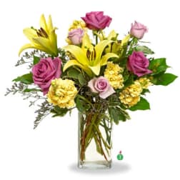 Tall arrangement of yellow lilies, yellow carnations, and lavender roses in a clear glass vase