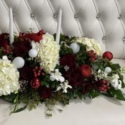 Low floral centerpiece with white hydrangeas, red roses, and candles