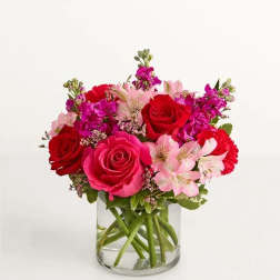 Bouquet of red and pink roses with pale pink alstroemeria in a clear glass vase
