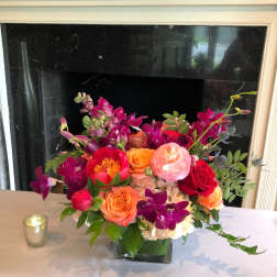 Colorful mixed flower arrangement in a square glass vase on a table