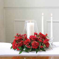 Red floral centerpiece with three white candles in glass holders