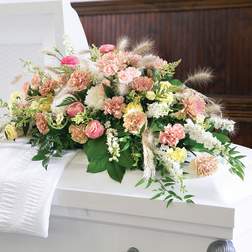 Pastel floral spray on a white casket