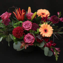Mixed bouquet with pink roses, orange gerbera daisies, and red blooms
