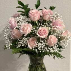 Pink roses arranged in a clear glass vase with baby's breath