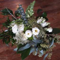 White floral bouquet with eucalyptus and greenery on a wooden floor