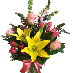Bouquet of yellow lilies and pink roses in a glass vase with a pink ribbon