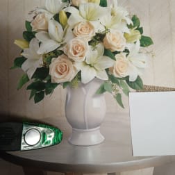 White lilies and pale roses arranged in a white vase