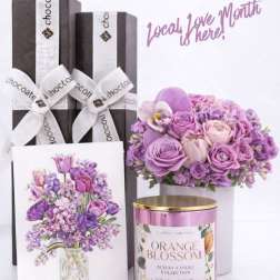 Gift set with purple flowers, chocolate boxes, and a pink candle