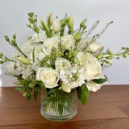 White roses and mixed white flowers in a clear glass vase