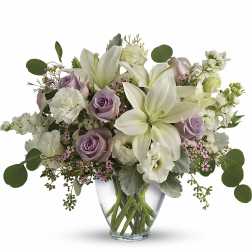White lilies and lavender roses in a clear glass vase