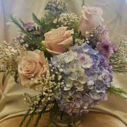 Bouquet of pale pink roses and lavender hydrangea in a glass vase