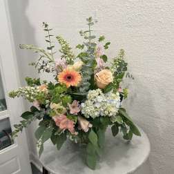 Mixed floral arrangement with peach roses, gerbera daisy, and hydrangea in a vase