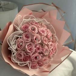 Pink rose bouquet wrapped in blush paper with pearl-edged tulle