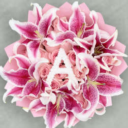 Pink lilies and roses arranged in a bouquet with pink wrapping