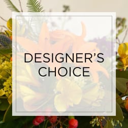 Colorful mixed bouquet with orange lilies and yellow blooms behind “Designer’s Choice” text overlay.