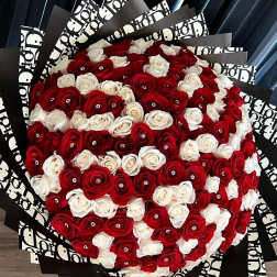 Large bouquet of red and white roses wrapped in black patterned paper