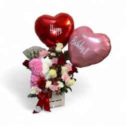 Heart balloons above a pink and white rose bouquet in a gift box