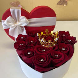 Heart-shaped box of red roses with a white ribbon bow and gold crown