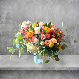Mixed bouquet of pink, peach, yellow, and white roses in a striped vase