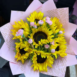 Bouquet of yellow sunflowers with small pink spray roses wrapped in pink paper