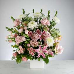 Tall arrangement of pink lilies, roses, and white mums in a white cube vase