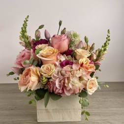 Mixed pink and peach flower arrangement in a white wooden box