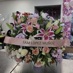 Large pink and white floral arrangement with a memorial ribbon
