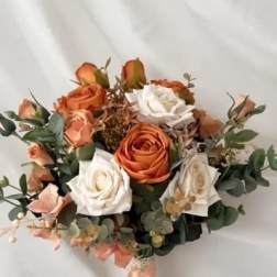 Bouquet of orange and white roses with greenery and a peach ribbon